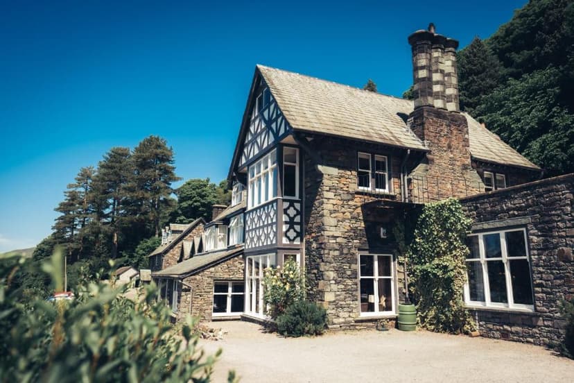 Stone building with Tudor revival details and large chimney against a bright blue sky.