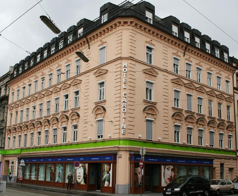 Hotel Caroline building exterior on a city street with overhead wires in Vienna