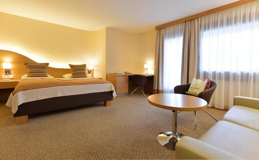 Seehotel Rust hotel room with large bed, desk, and seating area by window
