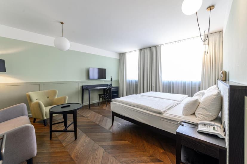 Hotel room with twin beds, light green walls, and chevron wood flooring in Hotel Caroline Vienna.