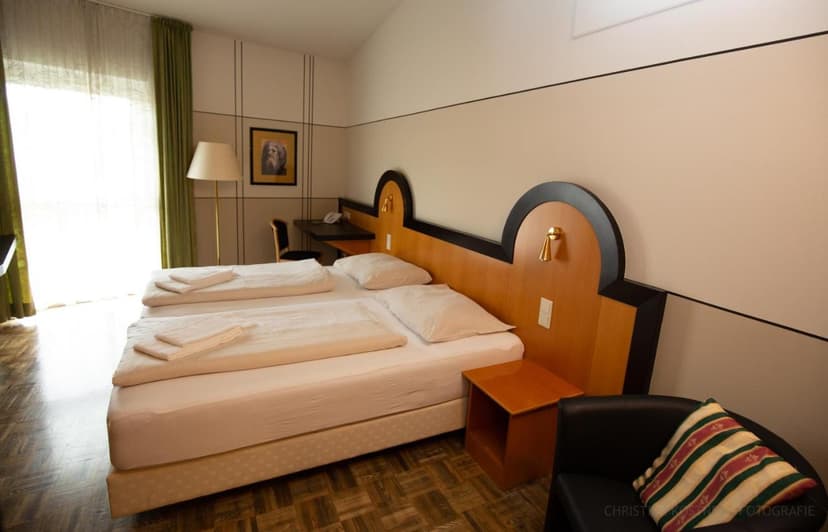 Twin beds in Hotel Fuchspalast room with bright window and wooden headboard.