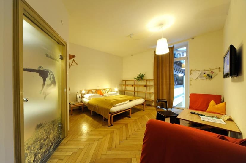 Brightly lit hotel room with wood floor, double bed, and frosted door featuring a leaping figure.