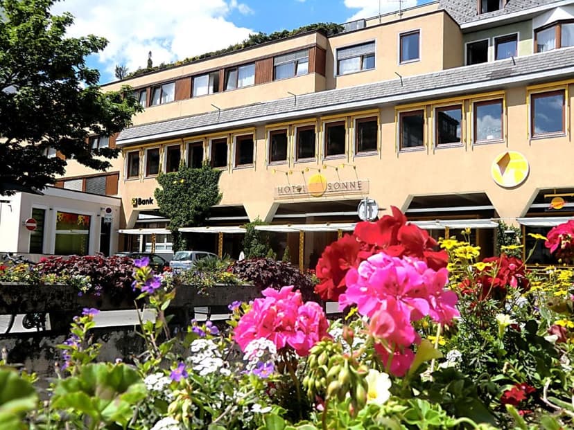 Hotel Sonne Lienz facade seen over bright pink, red, and yellow summer flowers.