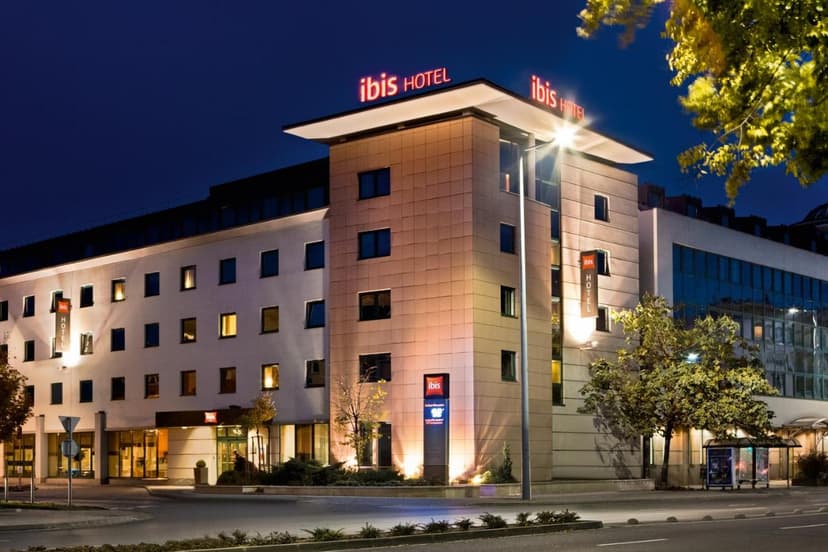 Ibis Hotel building illuminated at night with glowing red signage and street lighting in Győr.