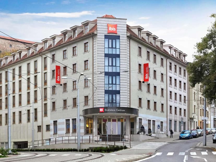 Ibis Bratislava Centrum hotel building on city street with tram tracks and parked cars.