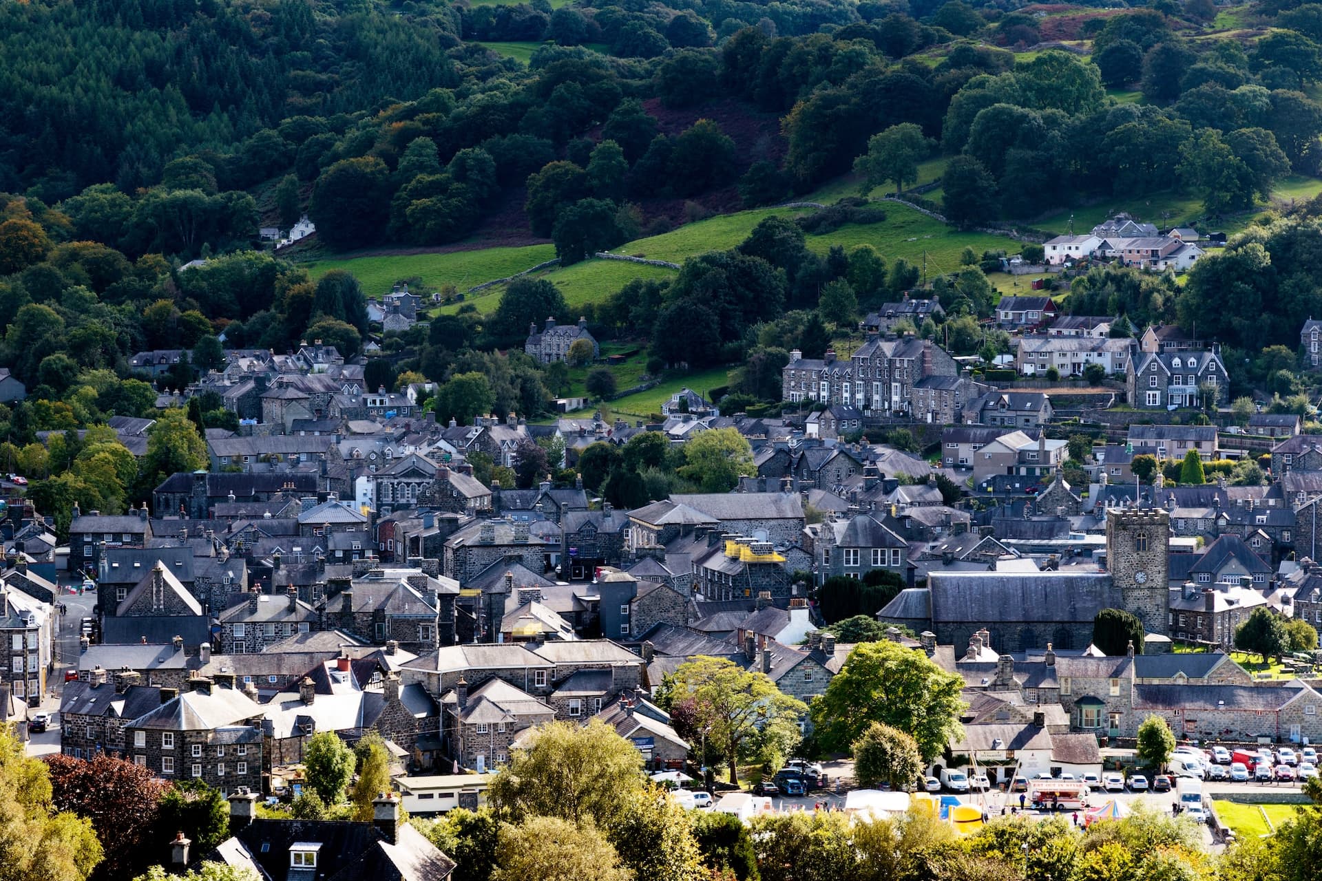 Town of Dolgellau nestled in green hills with dense forest backdrop.
