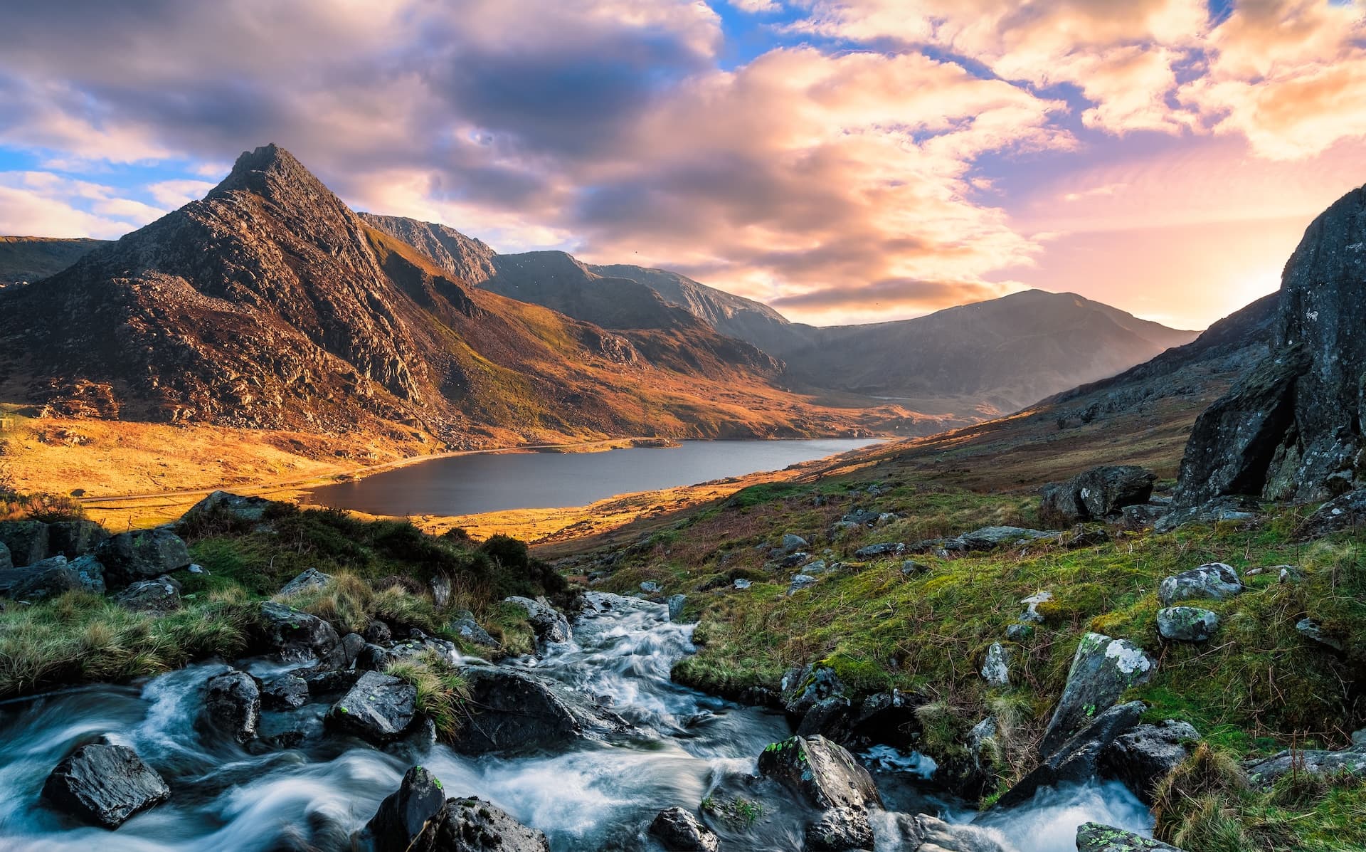 Mountain stream flowing past rocks toward a lake in Snowdonia at sunset