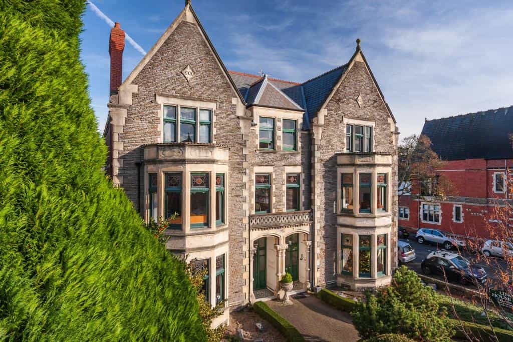 Stone Victorian-style building exterior, Lincoln House Private Hotel, with large green hedge.