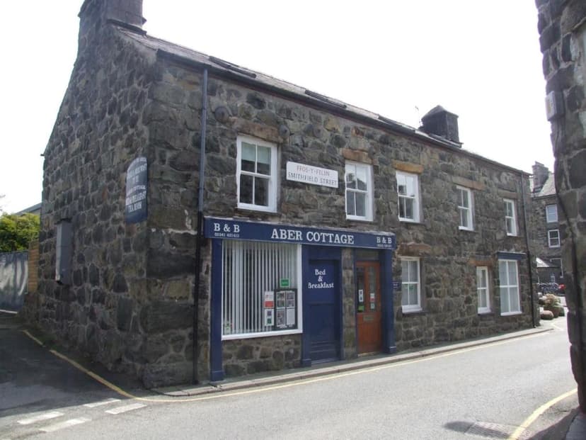 Aber Cottage Bed & Breakfast, a stone building on a street corner with white-framed windows.