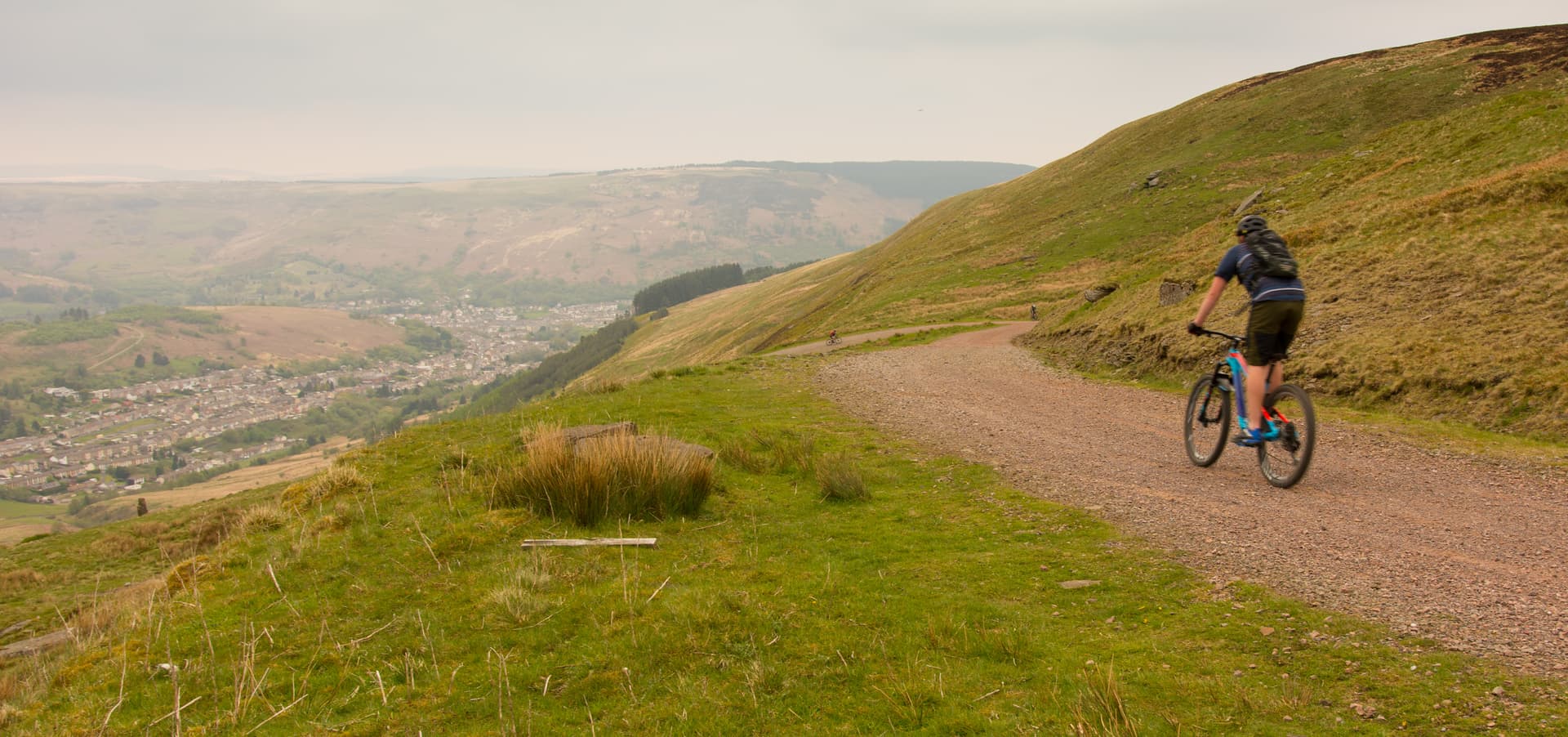 Mountain biking on a gravel track overlooking a valley town in Wales.