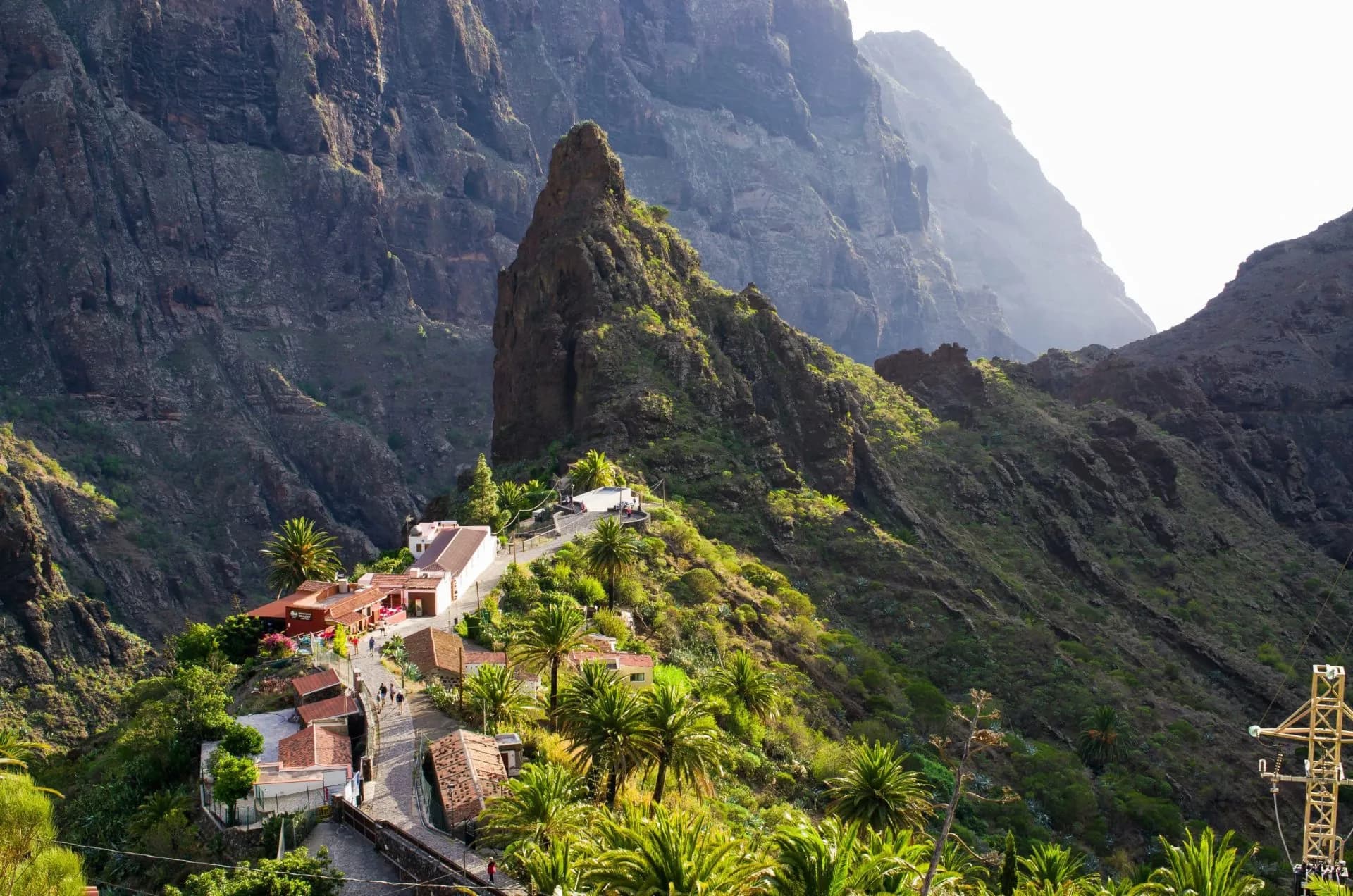 Village buildings nestled in steep green mountainsides around a prominent rocky peak in Masca, Tenerife.