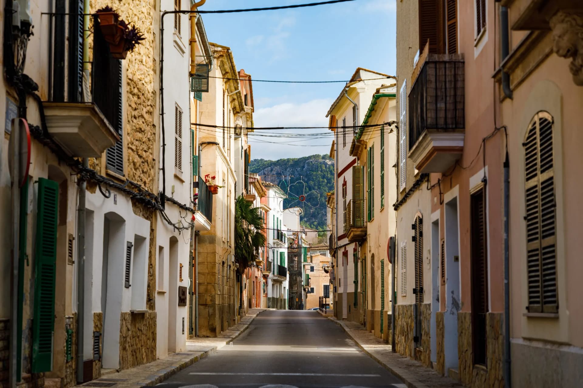 Narrow street in Andratx with traditional buildings and mountains visible in the distance