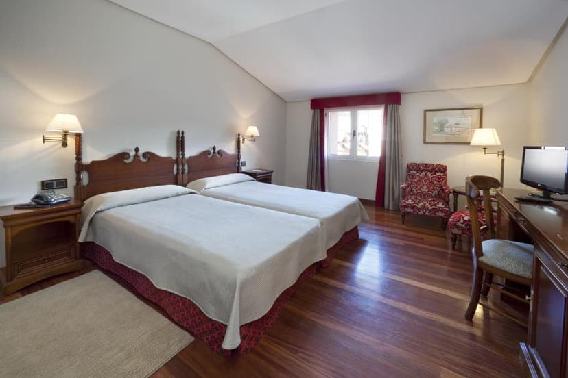 Twin beds with wooden headboards in a hotel room with wood floors at Parador de Las Cañadas del Teide.