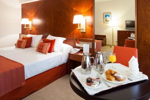Hotel room with large bed and room service breakfast tray featuring pastries and orange juice