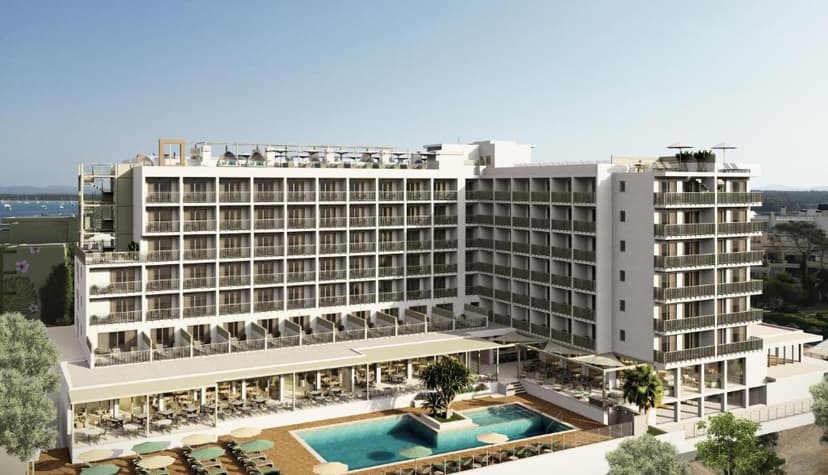 Large white hotel building with many balconies, pool, and outdoor dining near the sea.