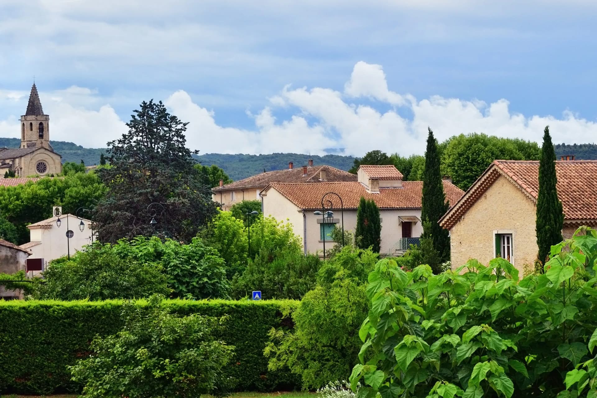 Medieval village of Mazan, Provence, France, with church tower and lush greenery after summer rain.