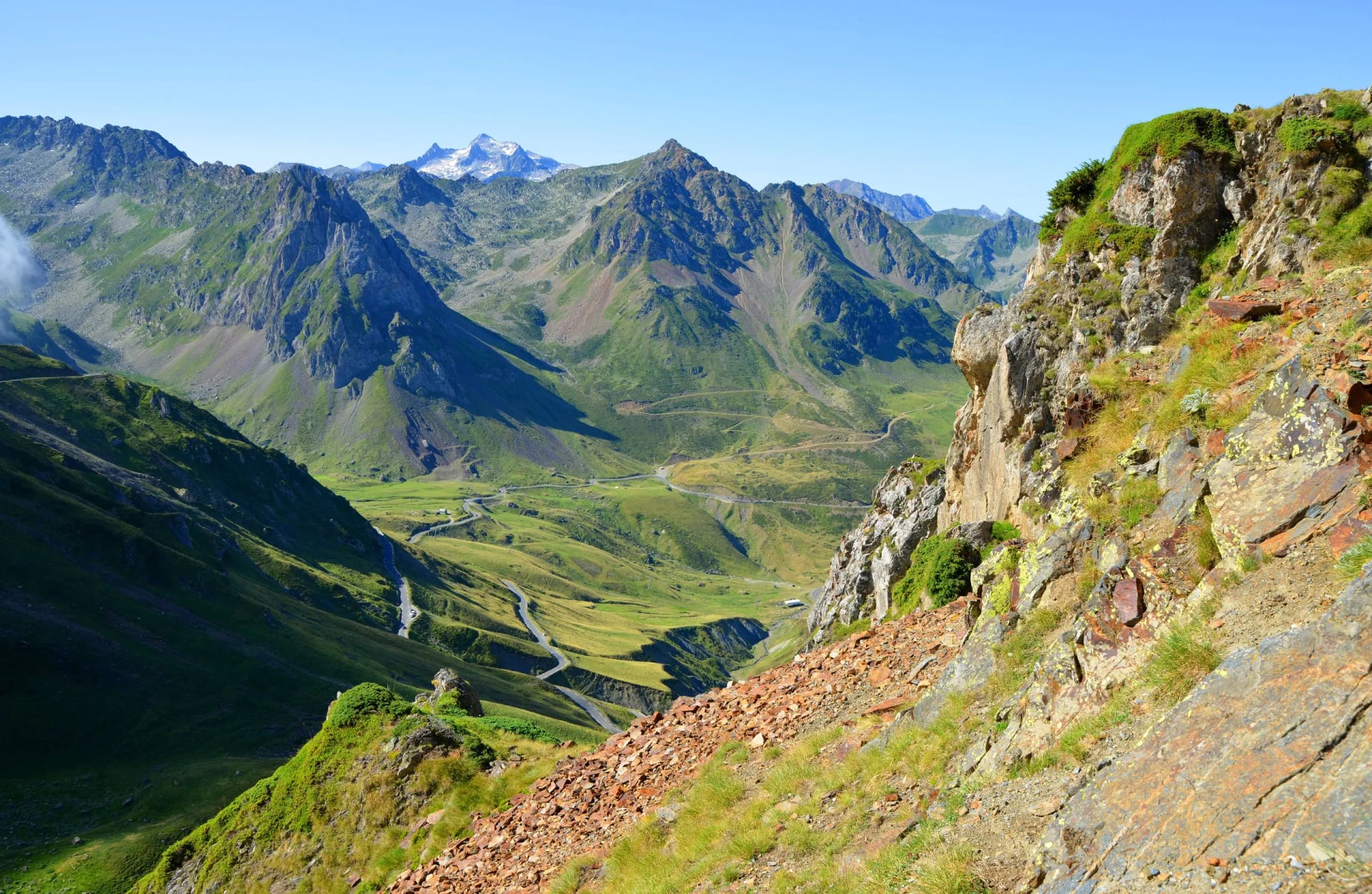 Winding mountain road through green valley at Col du Tourmalet in Pyrenees mountains, France