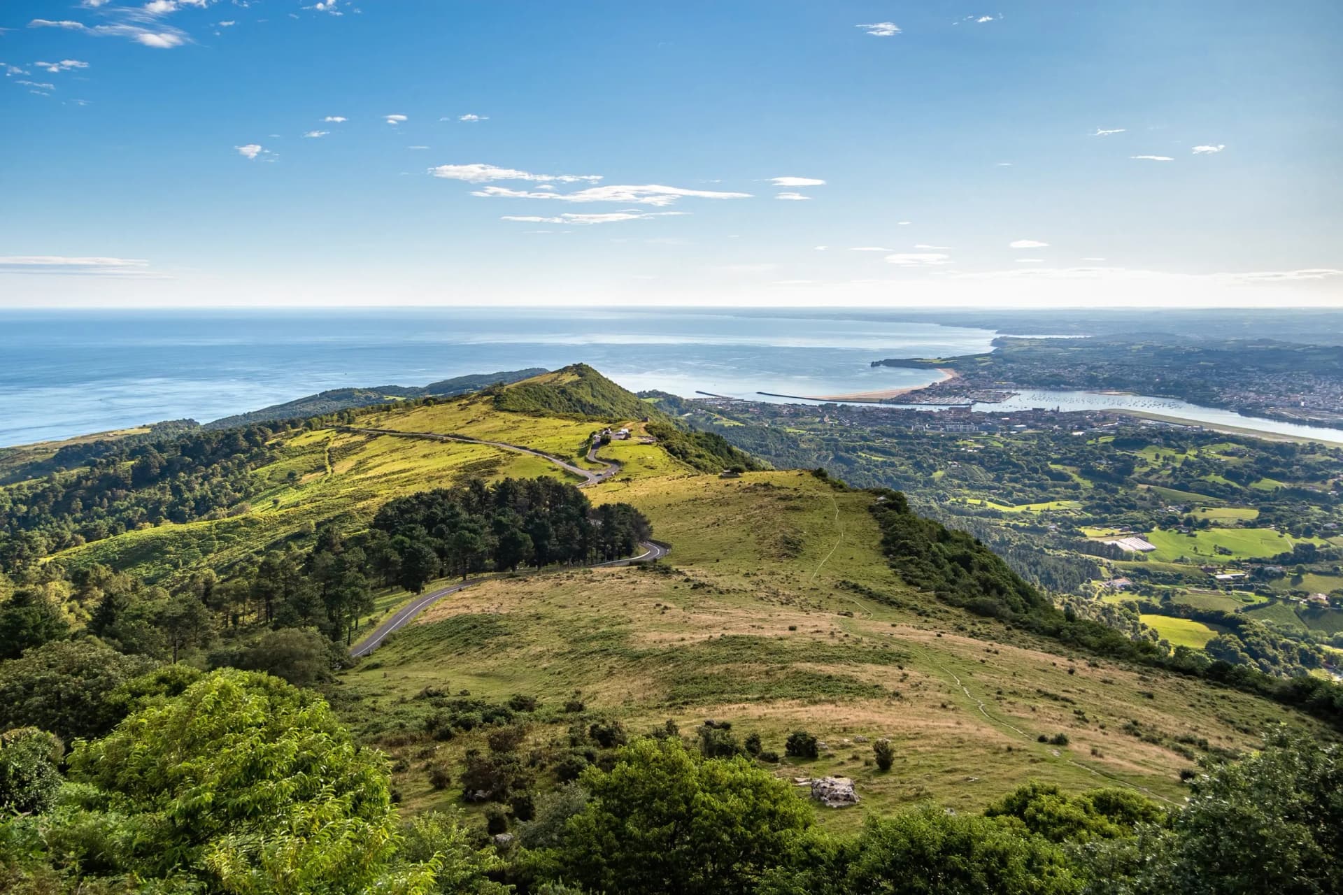 Panoramic view of green Basque Country hills, sea, and town, border Spain/France early morning summer.