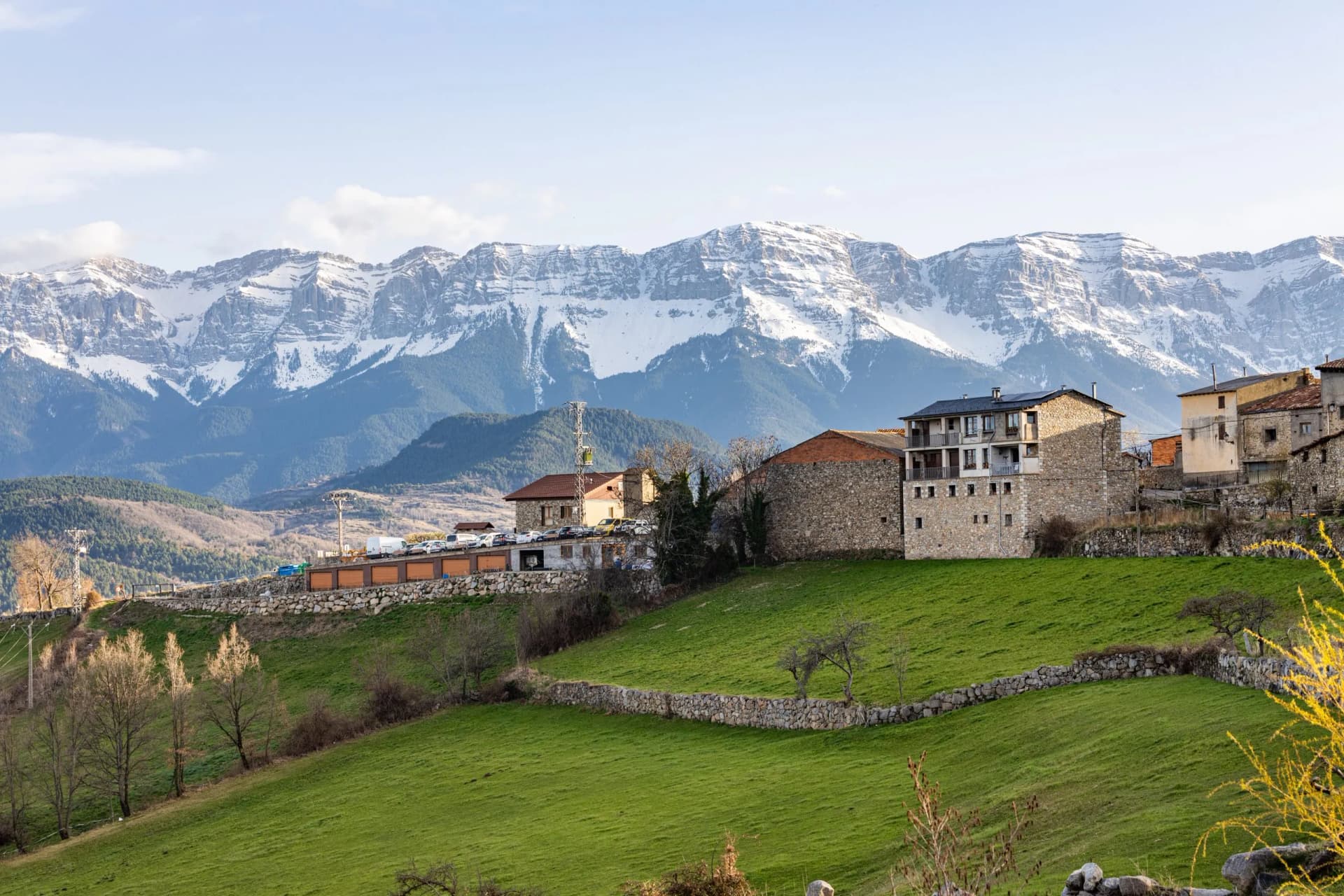 Stone village houses below snow-capped mountains in Les Cerdanya, Lleida, Catalonia, Spain.