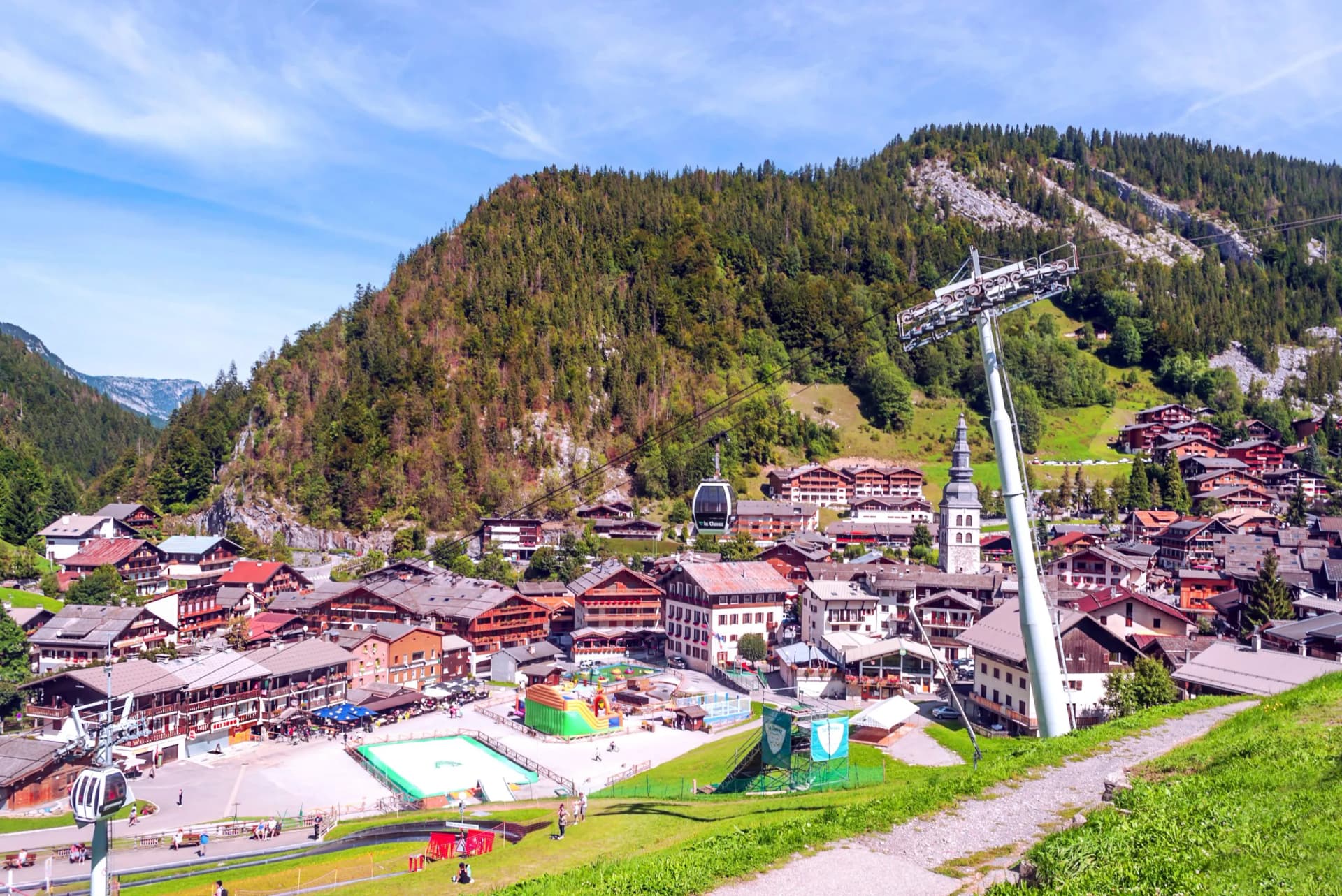 Alpine village of Megève, France, with chalets, a church tower, and a gondola lift tower.