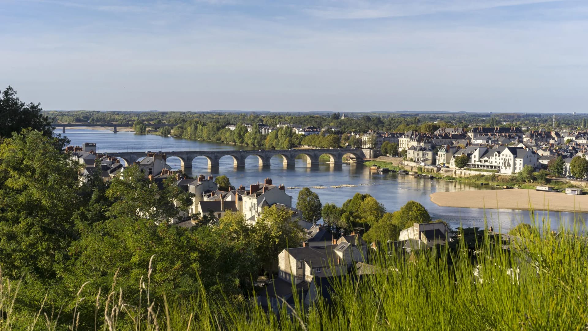 Views of Saumur, Maine-et-Loire, showing the town, river, and arched bridge under a clear sky.