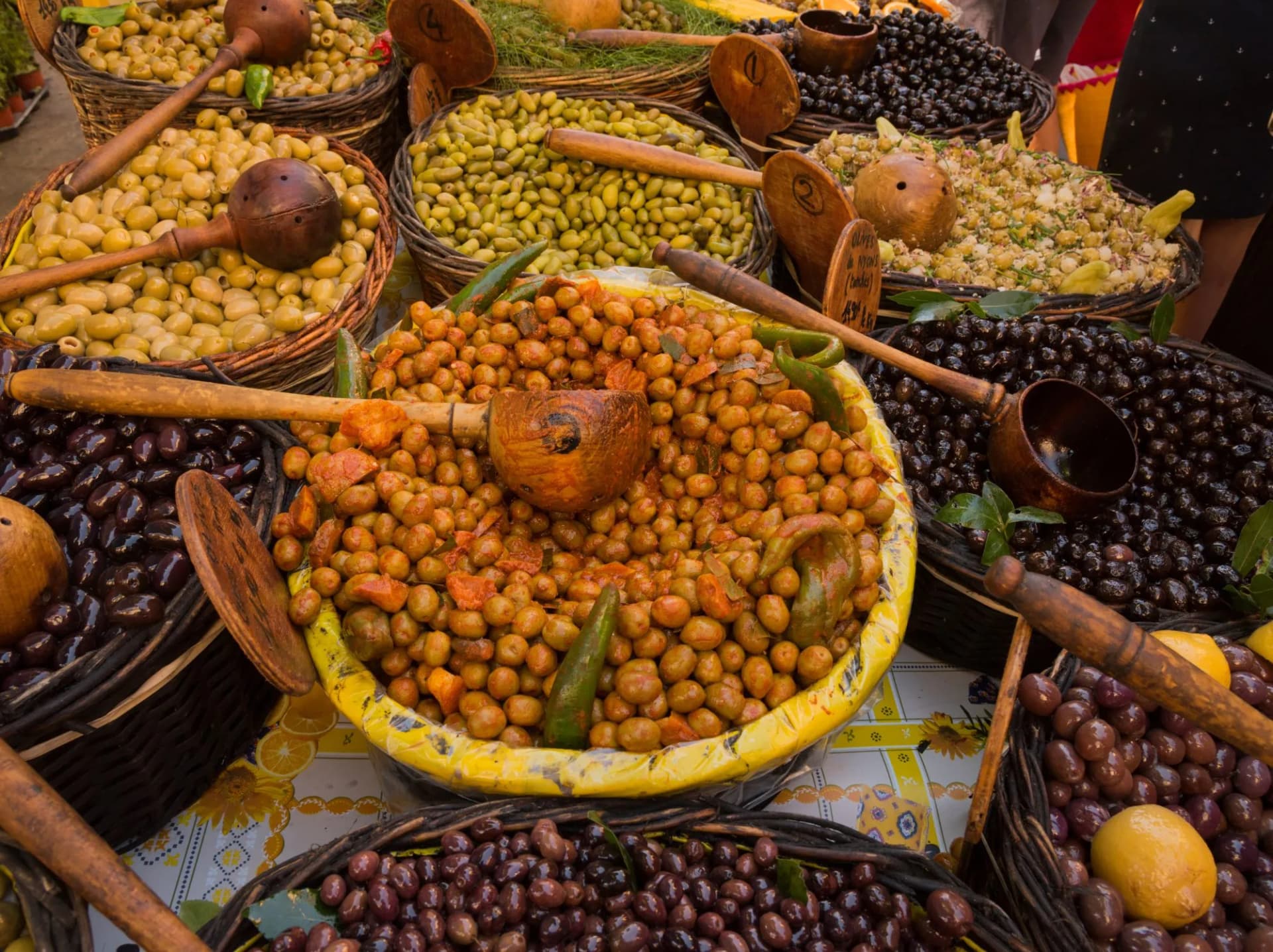 Baskets of marinated and fresh olives with wooden scoops at a market in Saint-Remy-de-Provence.