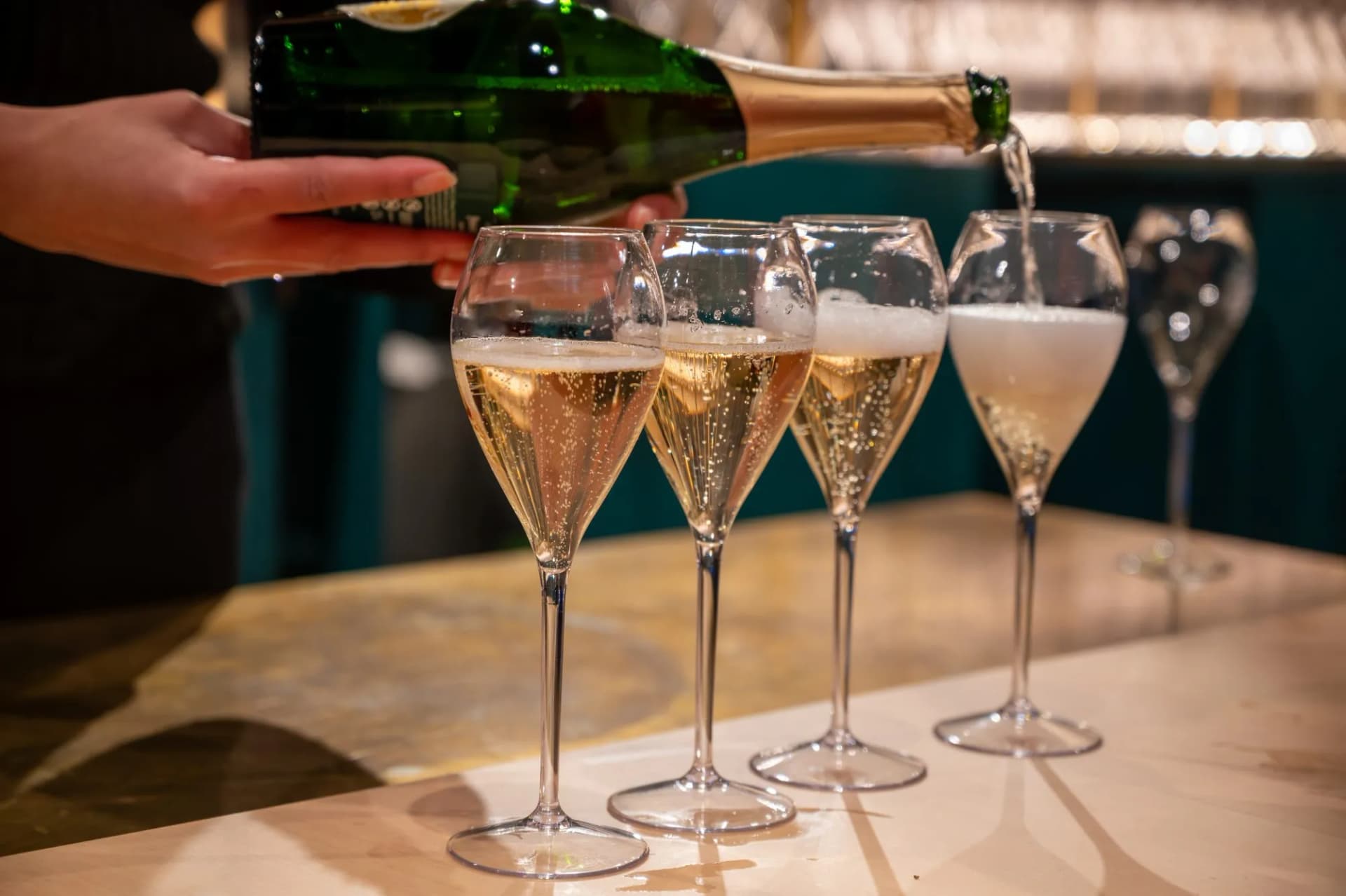 Pouring sparkling wine from a bottle into flutes during a tasting in Epernay, Champagne.