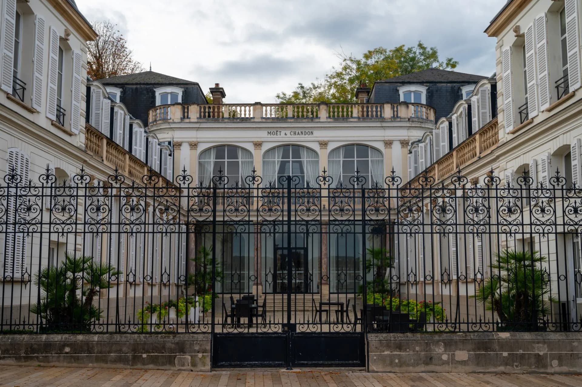 Moët & Chandon building facade seen through ornate black wrought iron gates in Epernay.