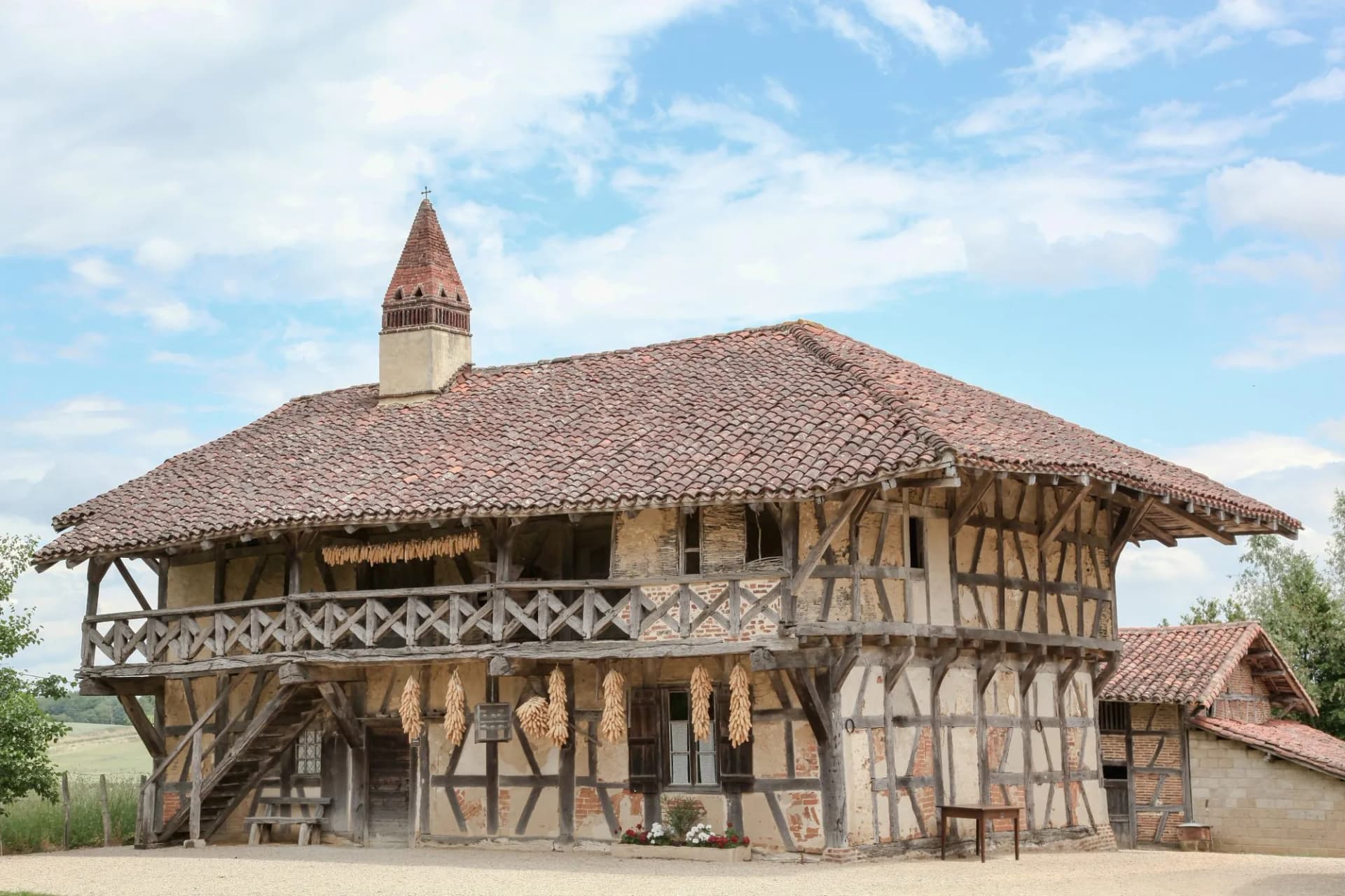 Historic Bressan farmhouse with half-timbering, terracotta roof, and drying corn cobs.