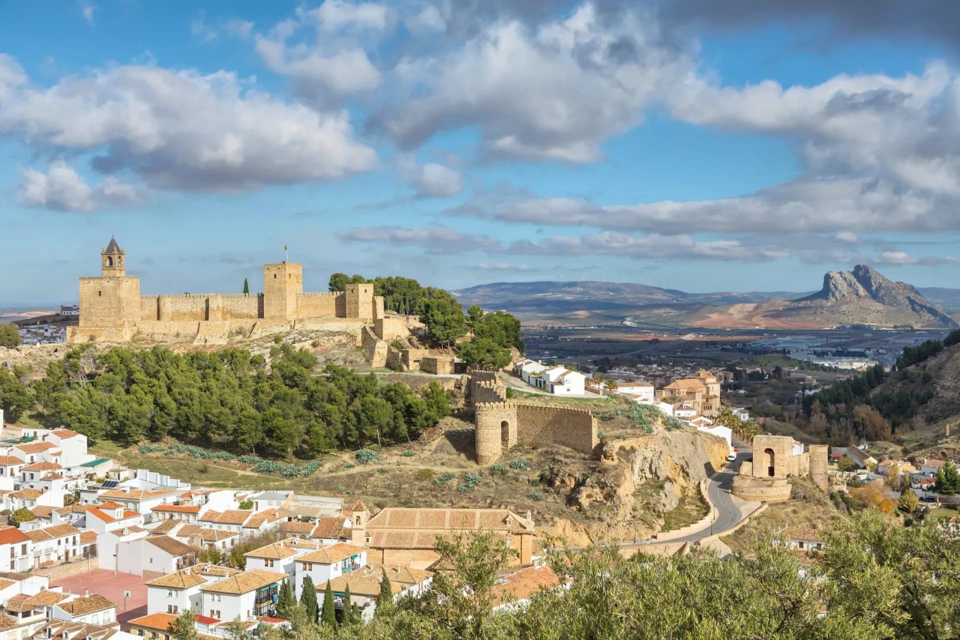 Alcazaba fortress above Antequera town, with white houses and a rocky mountain in the distance.