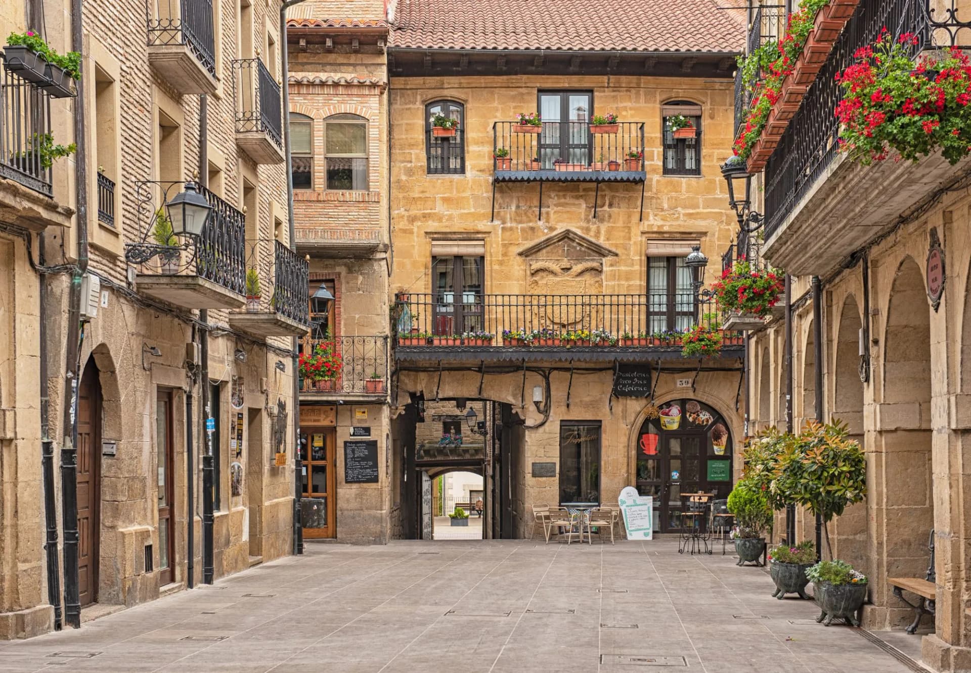 Old town street in La Guardia, Spain, with stone buildings, balconies, and flower boxes.