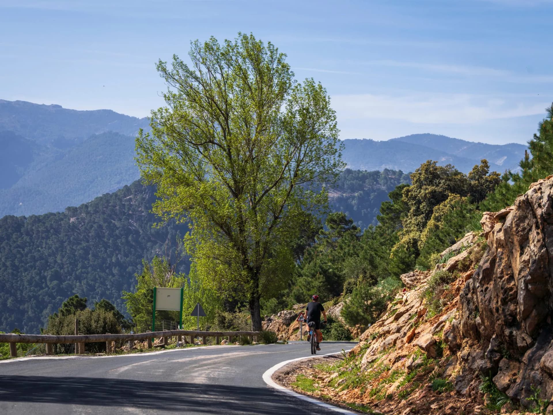 Cyclist riding on a winding mountain road in the Sierras de Cazorla National Park, Jaén, Spain.