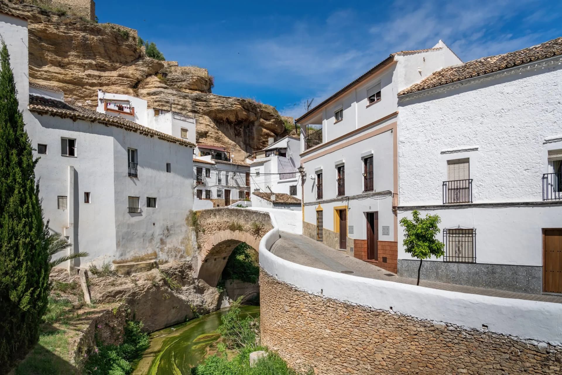 Bridge over Trejo River with white houses and rock overhangs in Setenil de las Bodegas, Andalusia, Spain.