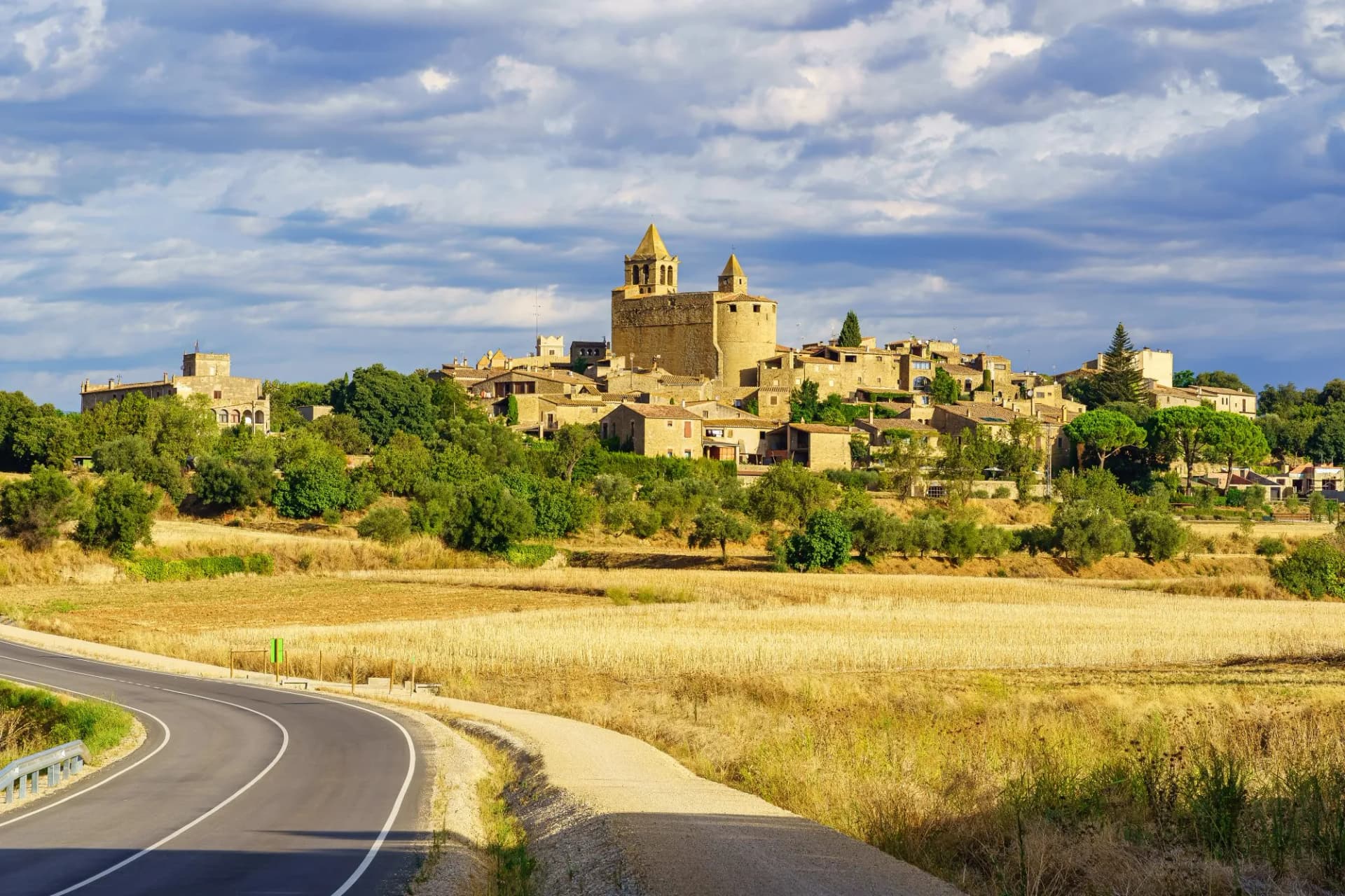 Panoramic view of the medieval village of Madremanya in Girona, Catalonia, Spain, above golden fields.