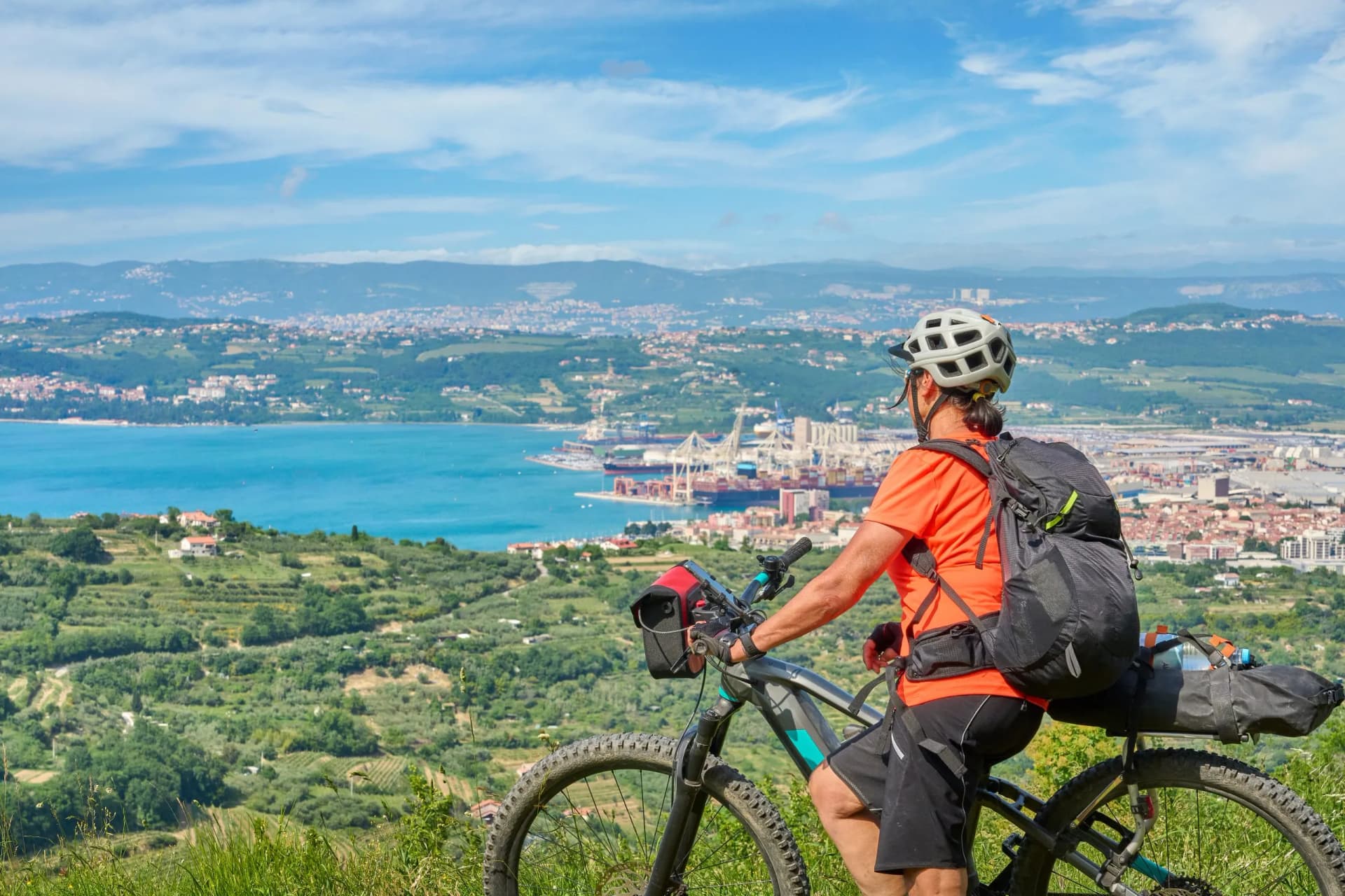 Mountain biker with backpack overlooking Koper at Capodistria on the Slovenian Mediterranean coast.