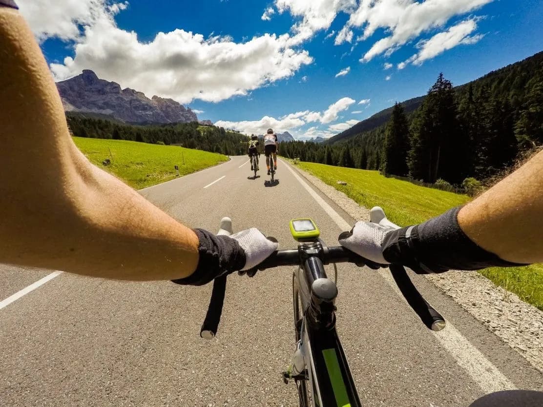 Road cycling on a paved mountain road with green hills and rocky peaks