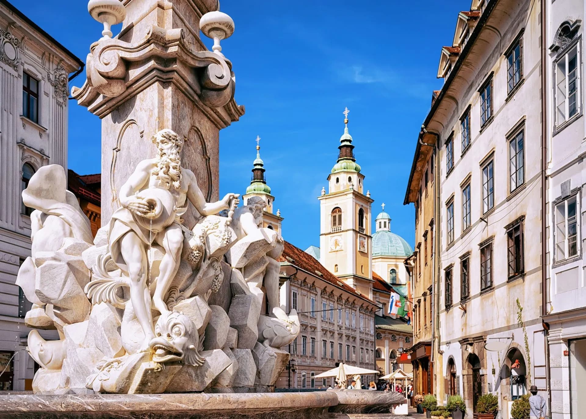 Robba Fountain sculpture in Ljubljana, Slovenia with historic buildings and church towers.