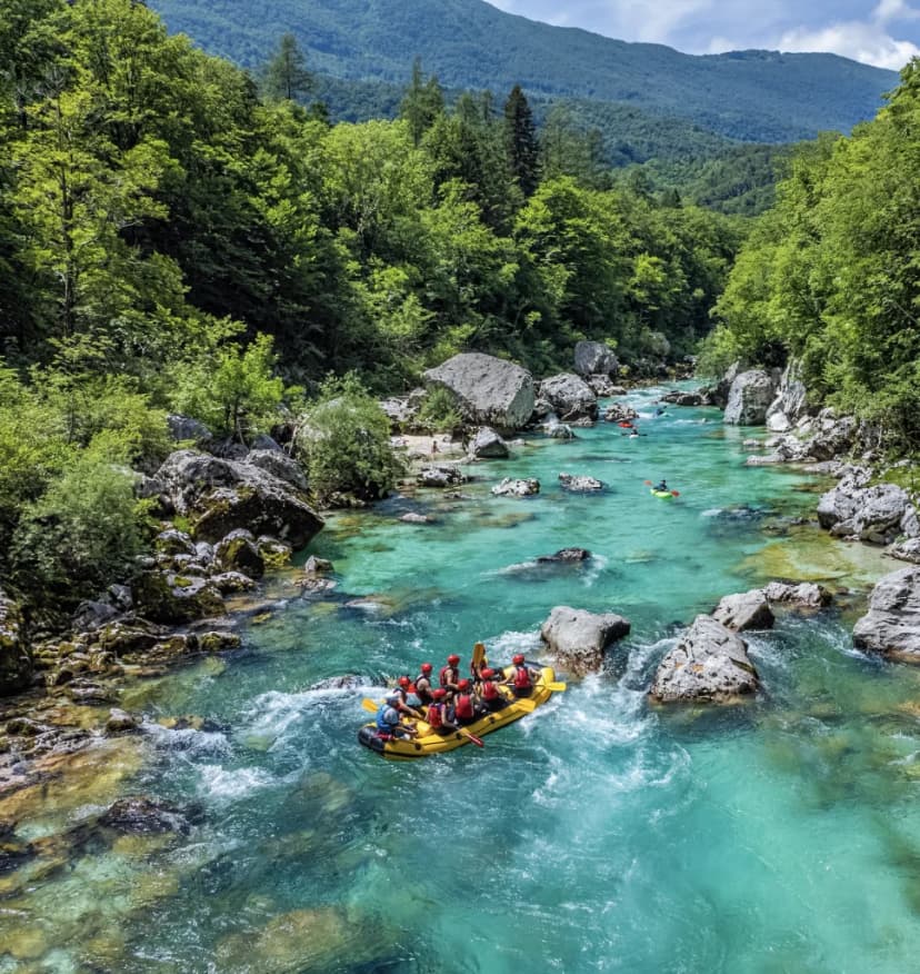Whitewater rafting group on turquoise river surrounded by lush green forest and mountains