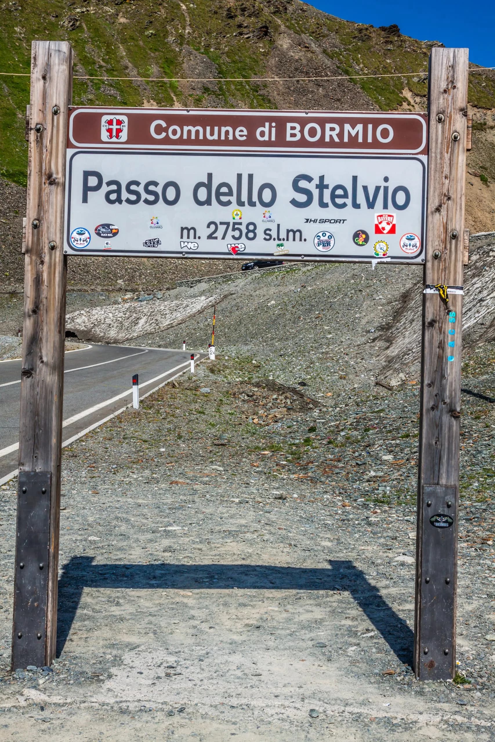 Passo dello Stelvio sign for Comune di Bormio at 2758m elevation with mountain road.