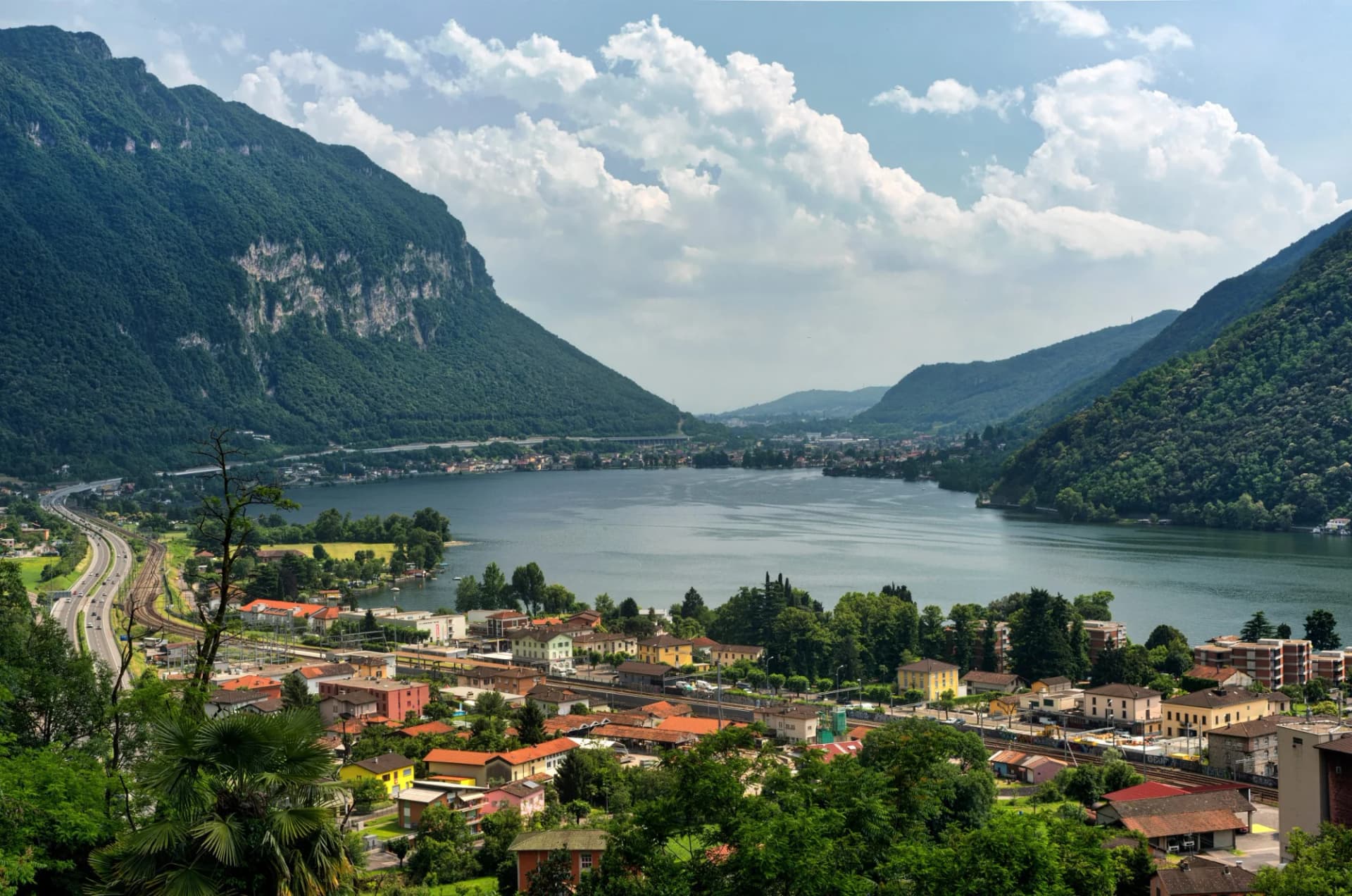 View of Ceresio Lake in Ticino, Switzerland, with green mountains and town below.