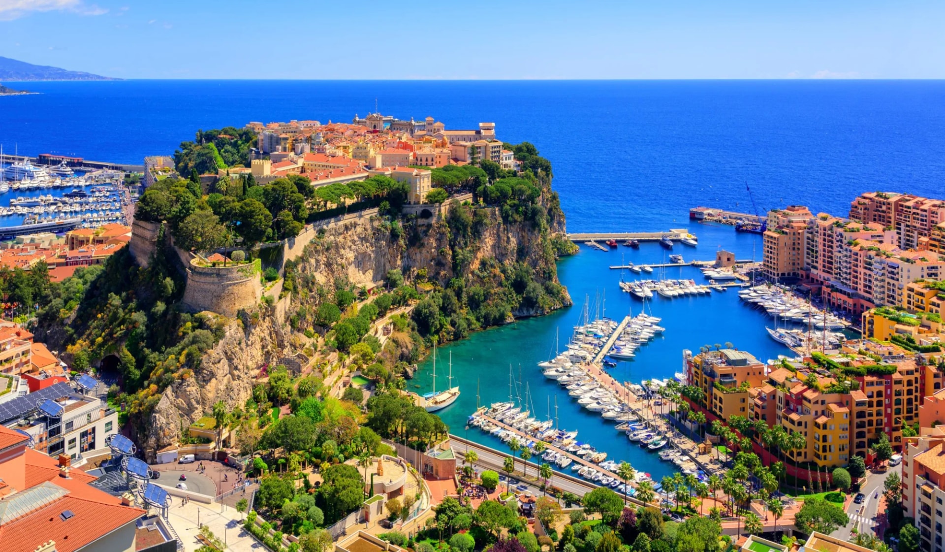 Prince's Palace and Old Town overlooking Monaco harbor filled with yachts on the Mediterranean coast.