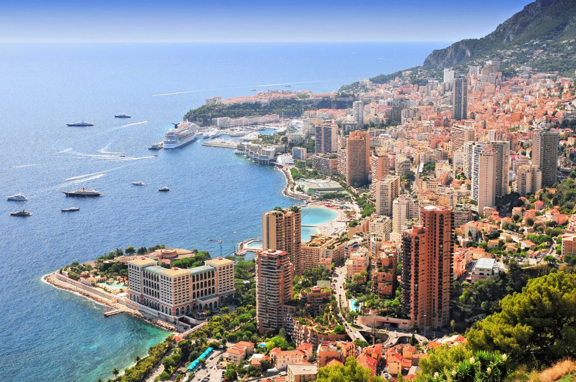 Elevated view over the city of Monte Carlo, Monaco, with high-rises, harbor, and yachts on the Mediterranean Sea.