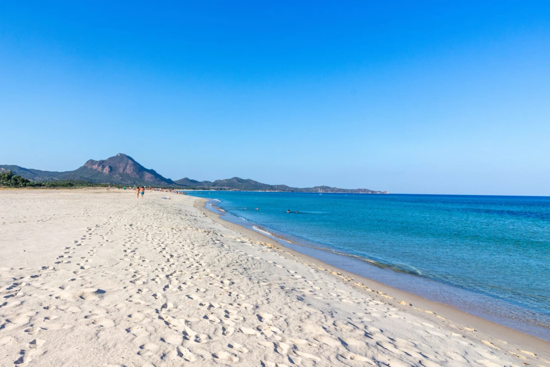 Wide white sand beach with turquoise water, mountains in the background, Costa Rei