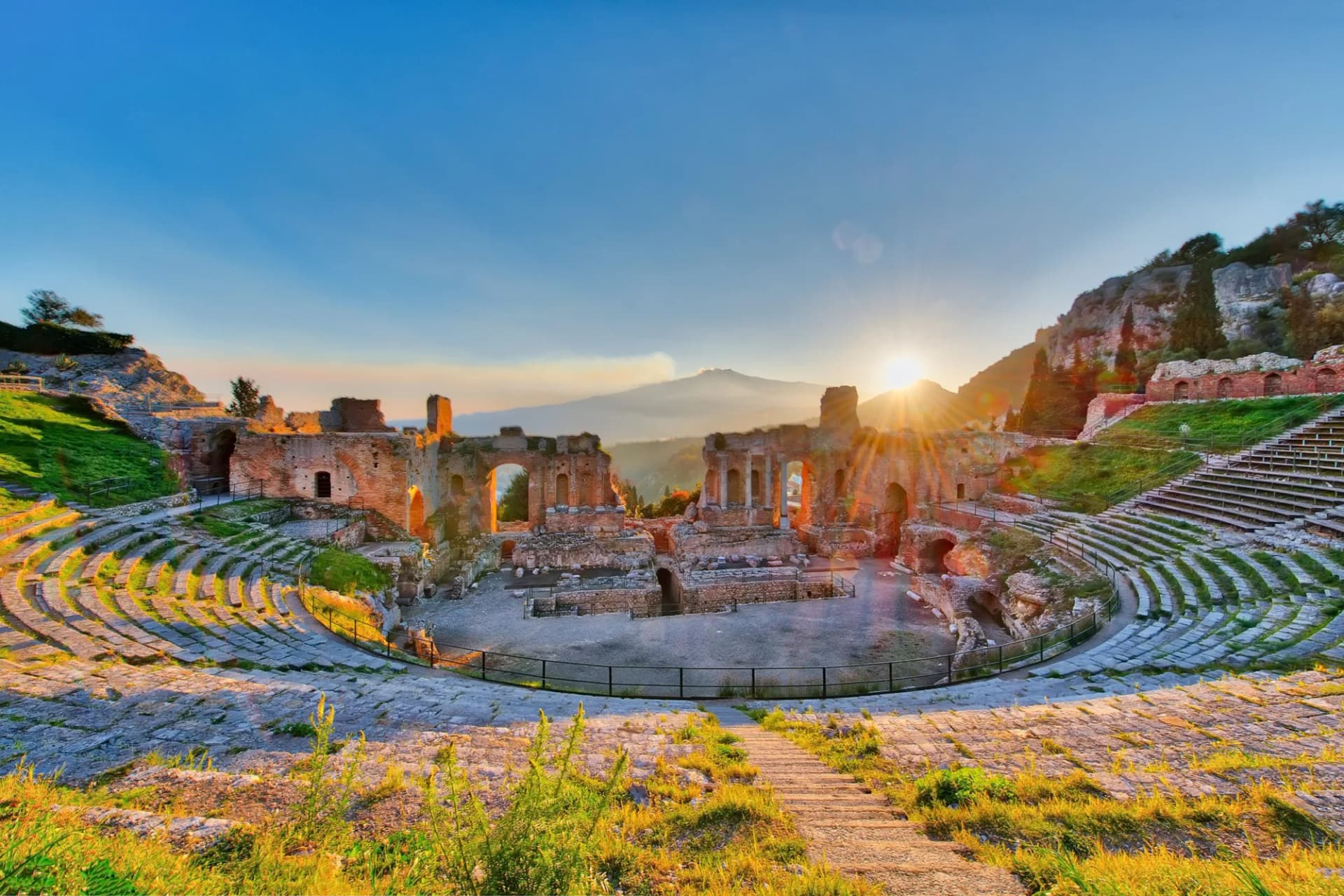Ancient Theatre of Taormina with Mount Etna erupting at sunset