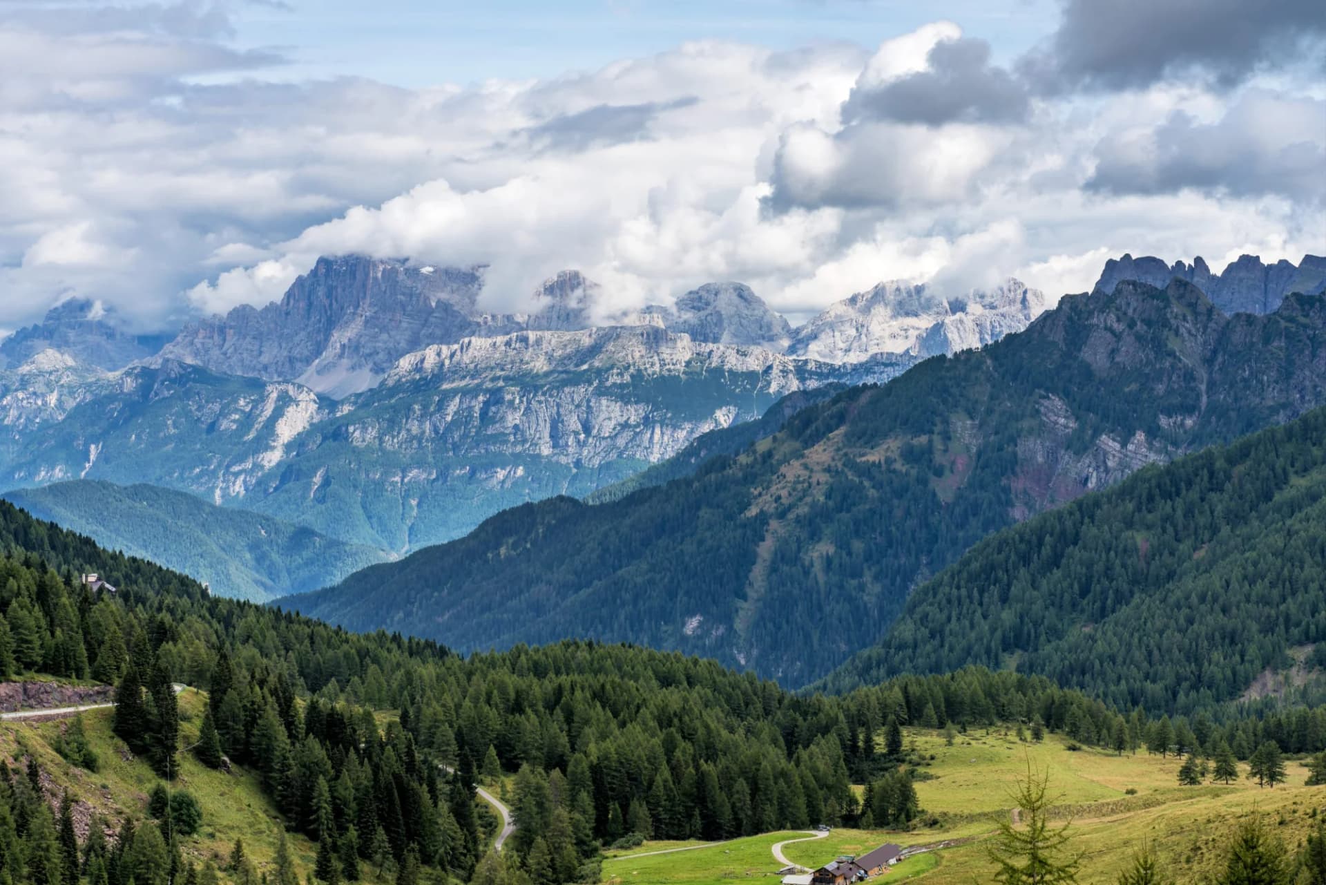 Alpine mountains with rocky peaks and green forested slopes in Val di Fassa, Trento, Italy.