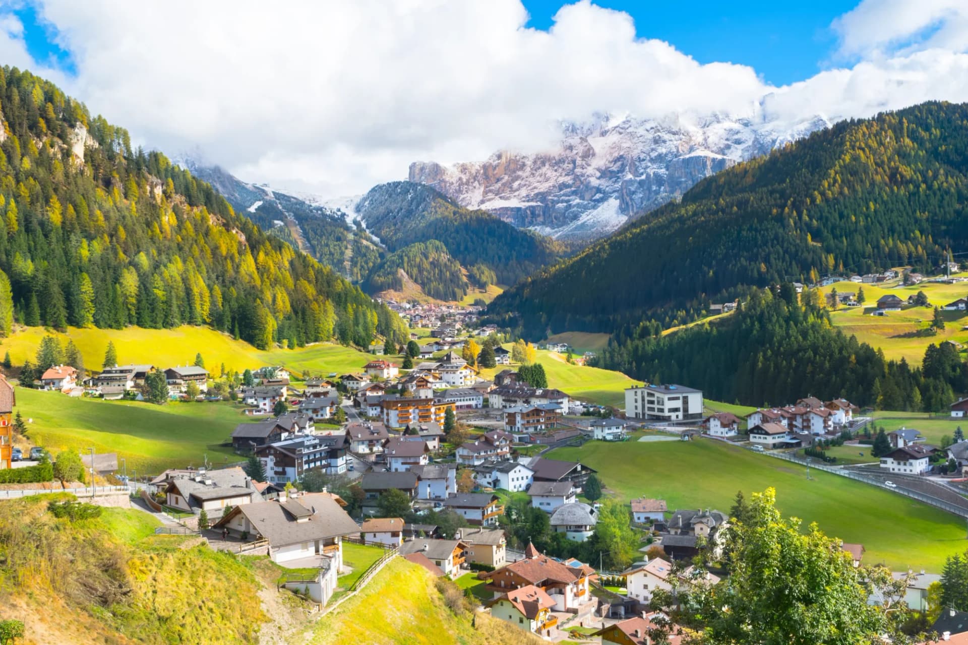 Santa Cristina Valgardena village nestled in green Val Gardena valley with snow-capped Dolomites.