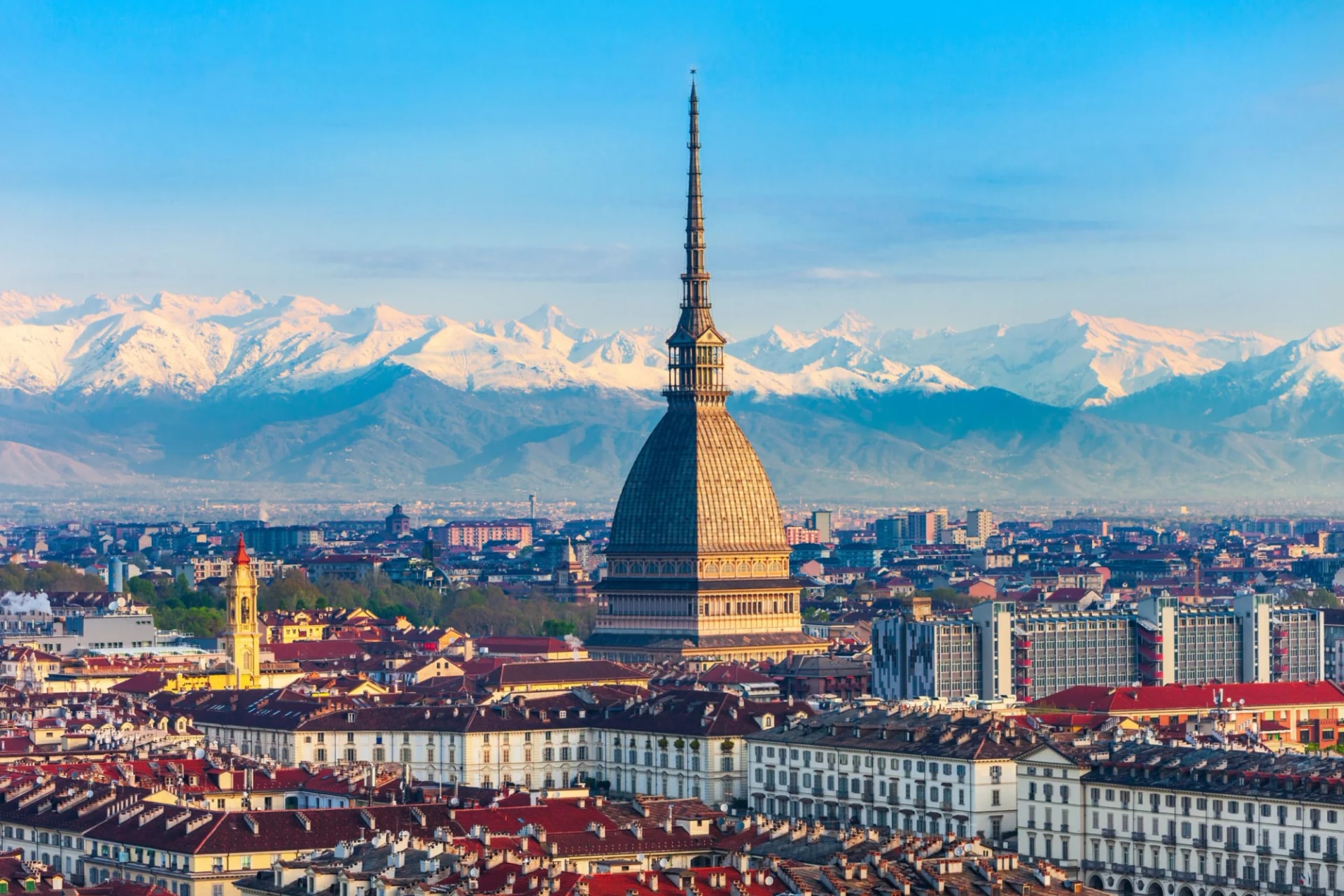 Mole Antonelliana towering over Turin cityscape with snow-capped Alps in background