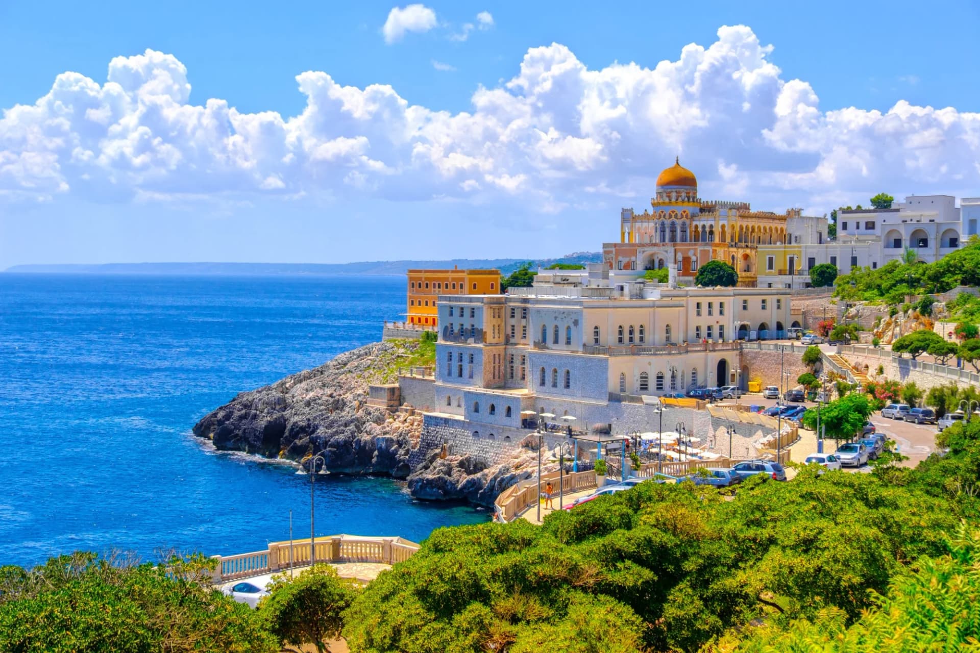 Coastal buildings in Santa Cesarea Terme, Salento, on rocky cliffs above bright blue Mediterranean Sea.