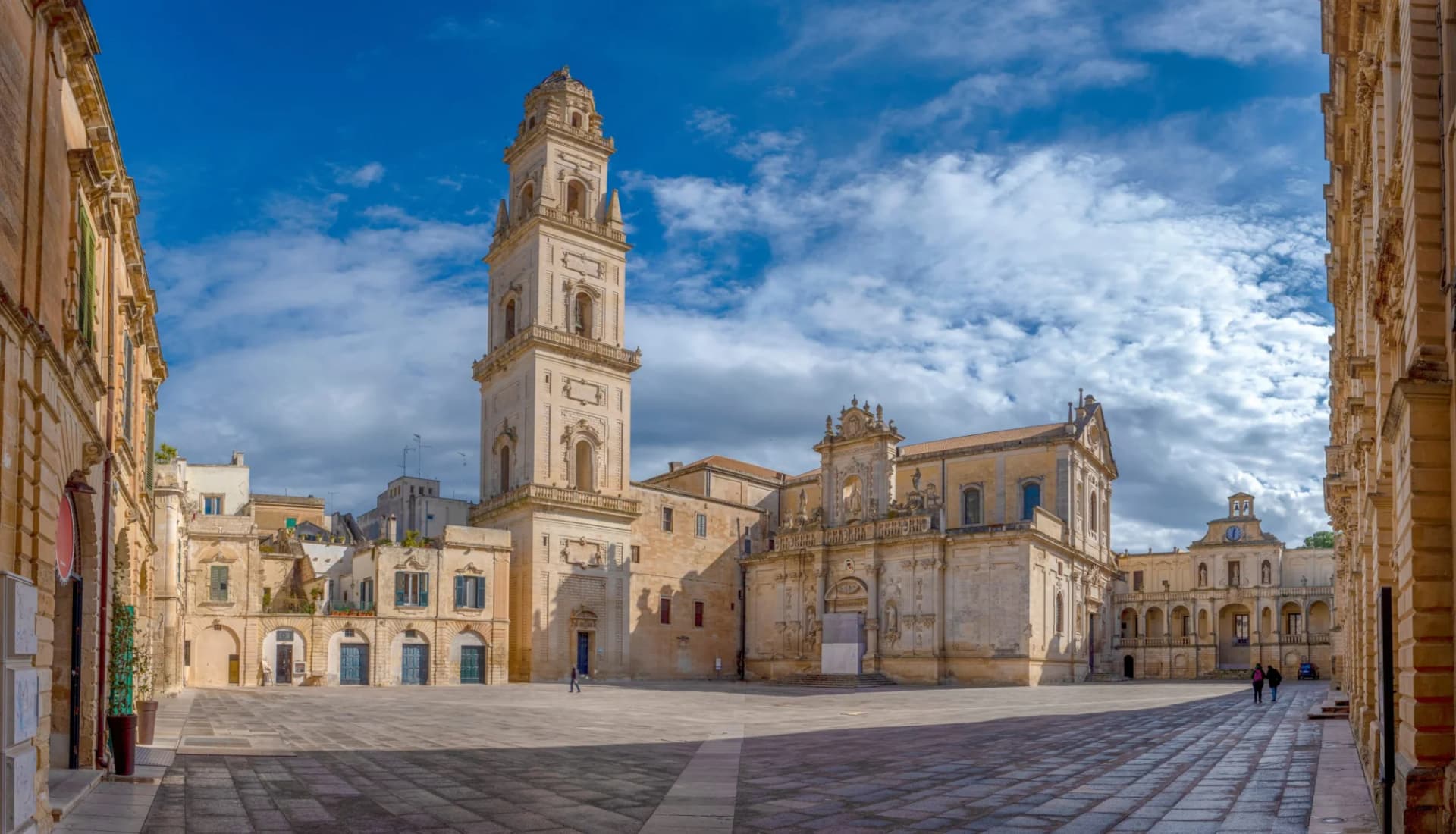 Piazza del Duomo with Campanile tower and Basilica in Lecce, Puglia, Italy under blue sky.