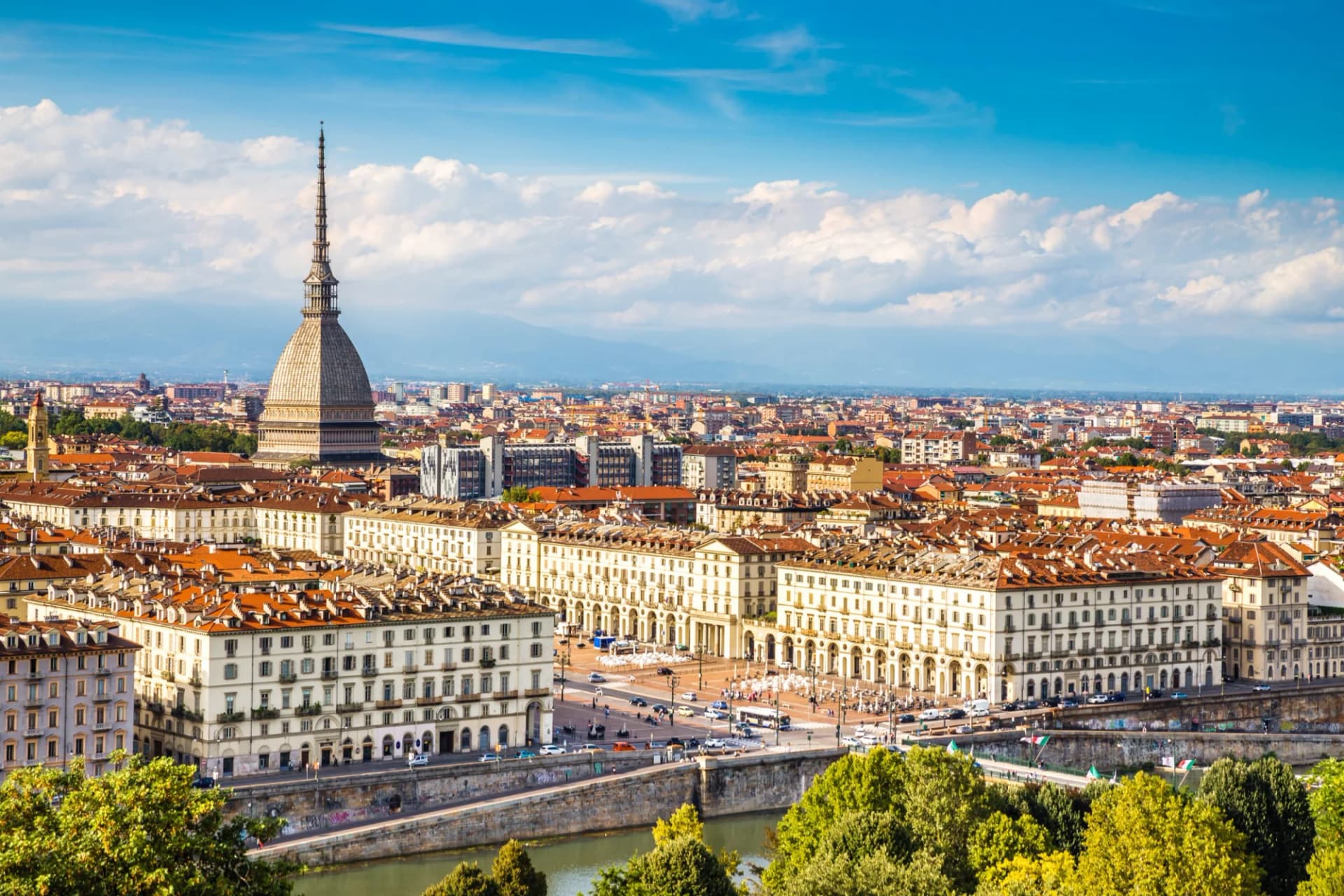 View of Turin centre with the Mole Antonelliana, historic buildings, and river on a sunny day.